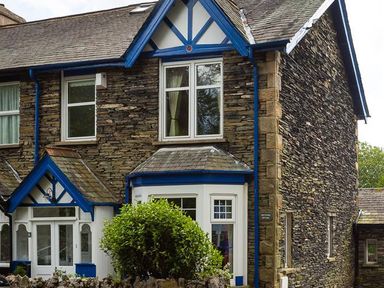 A stone house with blue painted wood trim and white framed windows at Ellerthwaite House in Windermere