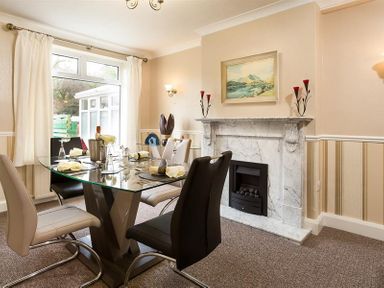 A dining room with a glass table and chairs near a fireplace at Heathfield in Keswick
