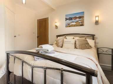 A bedroom with a metal bed frame white bedding pillows and folded towels at Heathfield in Keswick