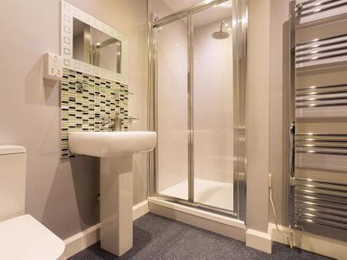 A bathroom with a pedestal sink a shower enclosure and a towel warmer at Heathfield in Keswick