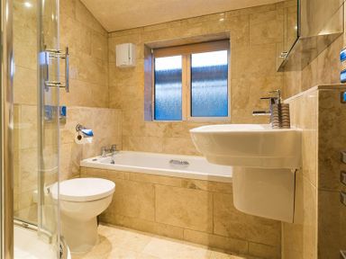 A bathroom with a toilet shower bathtub sink and a window at Heathfield in Keswick