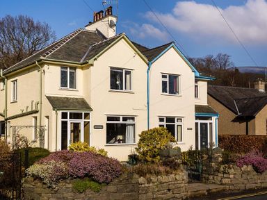 A semi detached house with stone wall and garden in front at Heathfield in Keswick