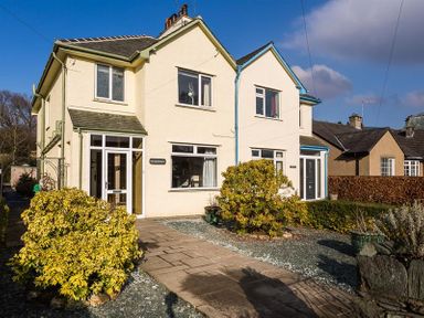 A two-story semi-detached house with a paved pathway and shrubs in front at Heathfield in Keswick