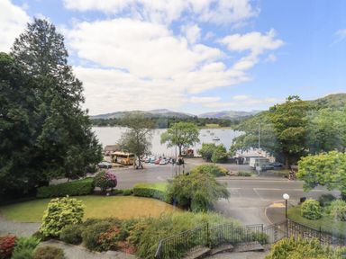 A view of a lake with boats trees a road and parked vehicles at Pure Grace in Ambleside