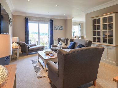 A living room with gray upholstered sofas a coffee table and a glass-front cabinet at Pure Grace in Ambleside