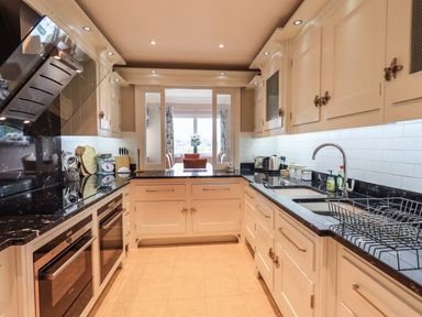 A kitchen with white cabinets black countertops and stainless steel appliances at Pure Grace in Ambleside