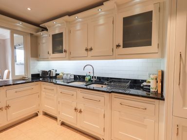 A kitchen with white cabinets black countertops a double sink and a drying rack at Pure Grace in Ambleside