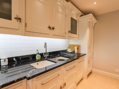 A kitchen with a dual sink black countertop white cabinets and tiled backsplash at Pure Grace Ambleside