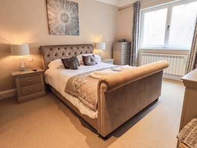 A bedroom with a bed nightstands lamps and a window at Pure Grace in Ambleside