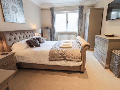 A bedroom with a bed pillows bedside tables a dresser wardrobe and a window at Pure Grace in Ambleside