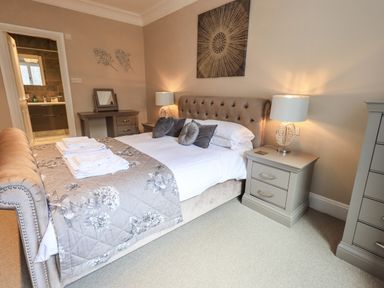 A bedroom with a bed with pillows and folded towels bedside tables with lamps and a dresser at Pure Grace in Ambleside