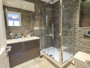 A bathroom with a shower enclosure a sink with cabinet and a toilet at Pure Grace in Ambleside