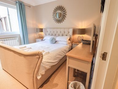A bedroom with a bed table lamps a mirror and a television on a dresser at Pure Grace in Ambleside