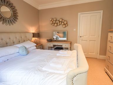 A bedroom with a large bed bedside tables a dressing table and a chest of drawers at Pure Grace Ambleside