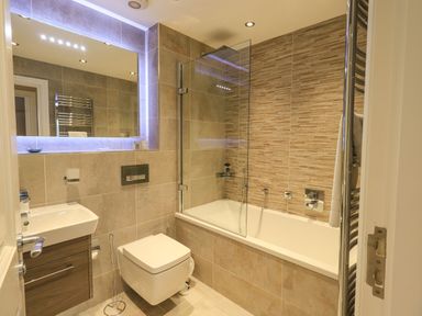 A bathroom with a bathtub shower combination a wall mounted toilet and a sink at Pure Grace in Ambleside
