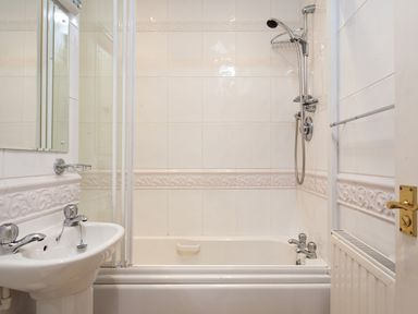 A bathroom with a bathtub shower combination sink and radiator at Honister Cottage in Ambleside
