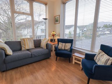 A seating area with a gray sofa and two blue armchairs with striped cushions at Windows in Ambleside