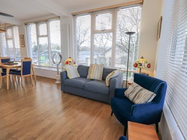 A living room with a blue sofa and armchairs and a dining table with chairs at Windows in Ambleside