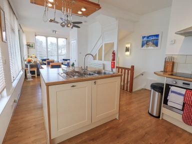 A kitchen with a central island and sink adjacent to a dining area with chairs and a window at Windows Ambleside
