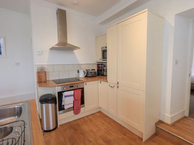 A kitchen with wooden floor cabinets a stainless steel oven stovetop and extractor hood at Windows in Ambleside