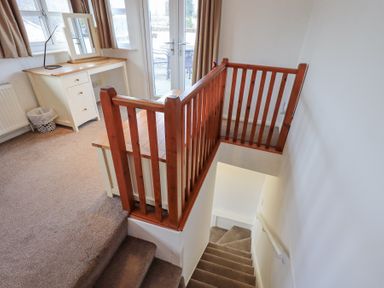 A carpeted stairway with wooden railing next to a white desk near a window and glass doors at Windows Ambleside