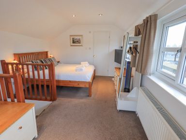 A bedroom with a wooden bed a chest of drawers and a window at Windows in Ambleside