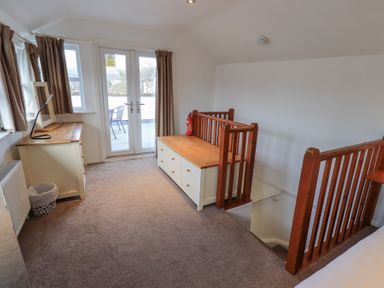An upstairs landing with a chest of drawers a wooden bench and stairs with wooden railings at Windows in Ambleside