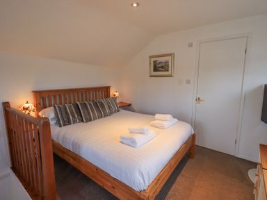 A bedroom with a wooden bed frame a white door and a painting on the wall at Windows in Ambleside
