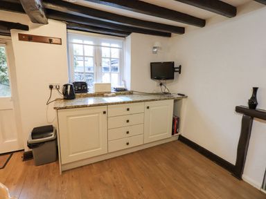 A kitchen counter with a kettle toaster bread box and a small wall mounted television at Cobblestone Cottage in Ambleside
