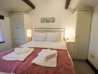 A bedroom with a double bed two white wardrobes and lamps at Cobblestone Cottage in Ambleside