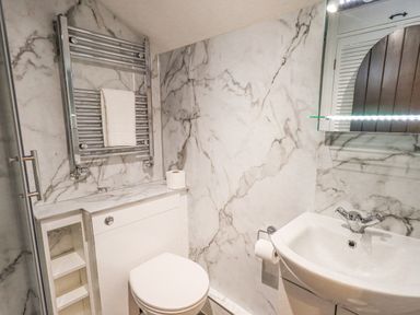 A bathroom with a toilet a sink a mirror and a towel rack at Cobblestone Cottage in Ambleside