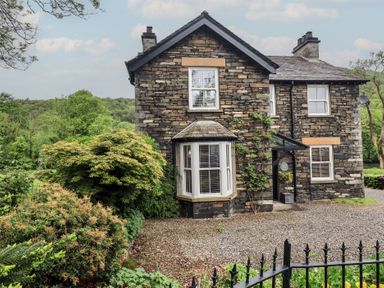 A house with a stone exterior and windows at Newby Bridge House in Newby Bridge