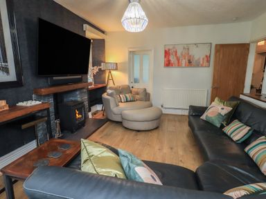 A living room with a television and sofa at Newby Bridge House in Newby Bridge