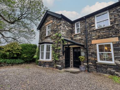 A stone building with an entrance and plants near the door at Newby Bridge House in Newby Bridge