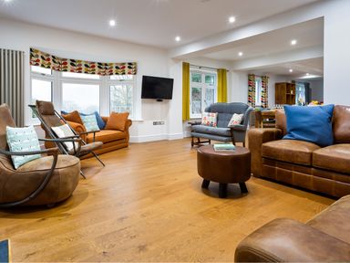 A living room with various sofas armchairs and a wall mounted TV at Wynford in Ambleside