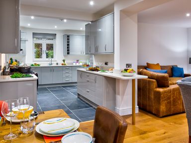 A kitchen with gray cabinets and a living room with a brown leather sofa at Wynford in Ambleside