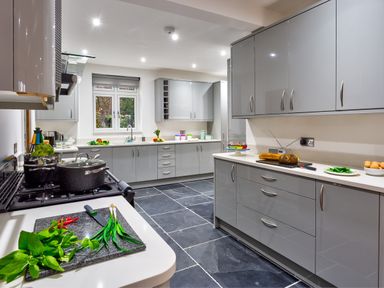 A kitchen with grey cabinets and black tiled floor with pots on stove and vegetables on counters at Wynford in Ambleside