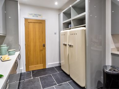 A kitchen with two cream SMEG refrigerators a wooden door and grey cabinets at Wynford in Ambleside