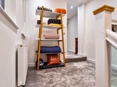 A carpeted hallway with a wooden shelf holding folded blankets and a cushion at Wynford Ambleside
