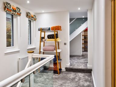 A hallway with carpeted floor and shelves holding folded blankets at Wynford in Ambleside