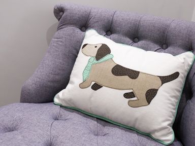 A cushion with a dog design on a purple tufted chair at Wynford in Ambleside