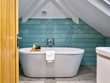 A bathroom with a white freestanding bathtub and teal tiled wall at Wynford Ambleside