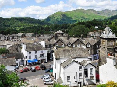 A town with stone and white buildings surrounded by green hills and mountains at Wynford in Ambleside