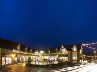 A shopping area with lit storefronts and string lights at Wynford in Ambleside