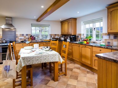 A kitchen with wooden cabinets and a table set with dishes and utensils at Horrockwood Farm in Watermillock