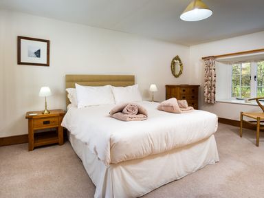 A bedroom with a bed towels bedside tables lamps a window and wooden furniture at Horrockwood Farm in Watermillock