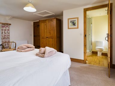 A bedroom with a bed towels wooden wardrobe open door to bathroom at Horrockwood Farm Watermillock