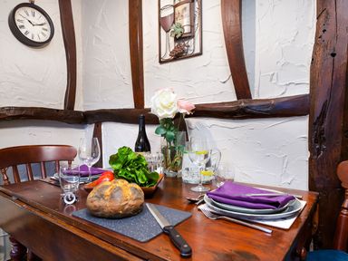 A dining table set with bread lettuce wine glass and purple napkins at Tipsy Gin Cottage in Crosthwaite