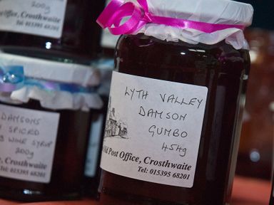 A close up of jars with handwritten labels on a table at Tipsy Gin Cottage Crosthwaite