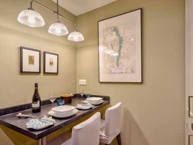 A small dining area with two white chairs and a counter set for two with dishes and wine at Barn End in Ambleside